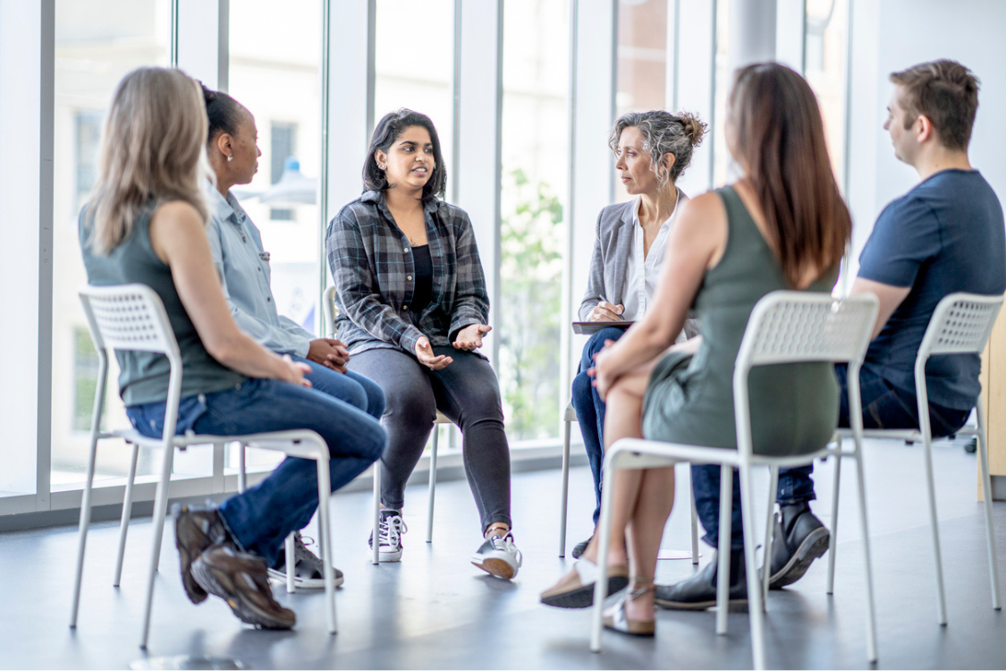 Several people sitting in a circle talking to one another, in casual clothes
